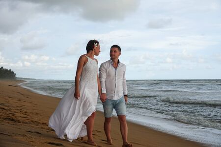Young couple in love walks on the beach at sunset, holding hands. The coast of Sri Lankaの写真素材