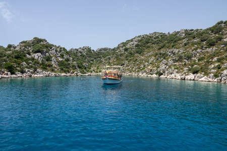 Kalekoy, Demre, Turkey - June 03, 2019: Swimming tourists near the pleasure yacht. The rocky coast of Kekova Island in the Mediterranean Seaのeditorial素材
