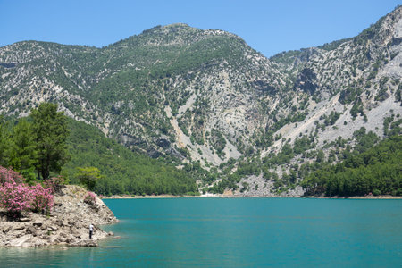 Manavgat, Turkey - June 05, 2019: A fisherman catches fish on a lake among mountain cliffs in the Green Canyonのeditorial素材