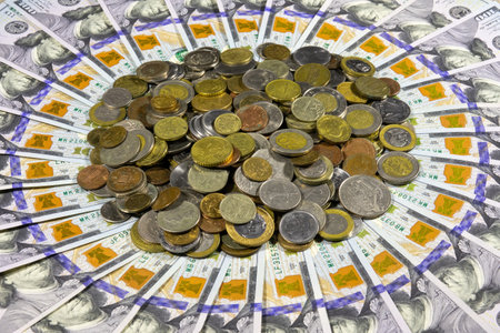 A bunch of different coins from around the world on the background of one hundred dollar bills of American dollars laid out in a circle. Banking and financial conceptの写真素材