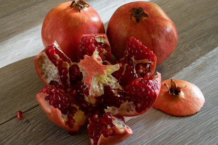 Two fresh ripe pomegranates and one cut on a gray wooden table. close-upの写真素材