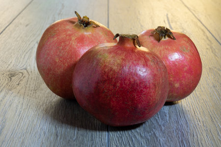 Three fresh ripe pomegranates on a gray wooden table. close-upの写真素材