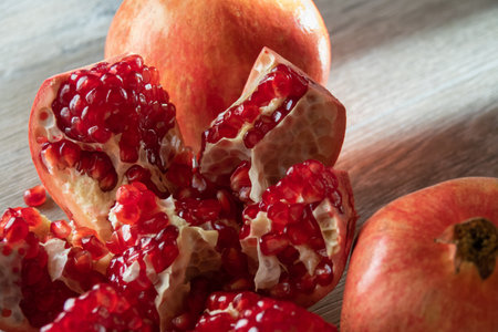 Two fresh ripe pomegranates and one cut on a gray wooden table. close-upの写真素材