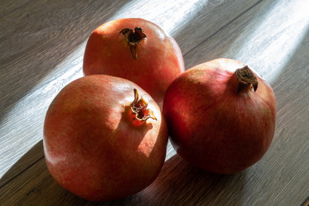 Three fresh ripe pomegranates on a gray wooden table. close-upの写真素材