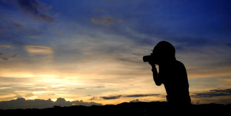 Shadow of woman taking photograph during sunsetの写真素材