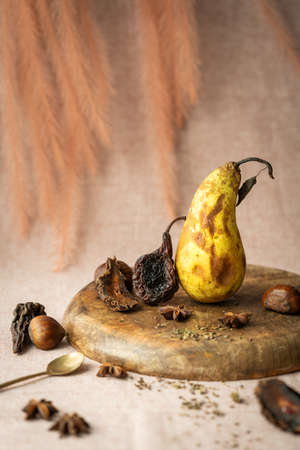 chestnuts and dried pear wedges and a very ripe pear with brown spots were arranged in a still lifeの写真素材