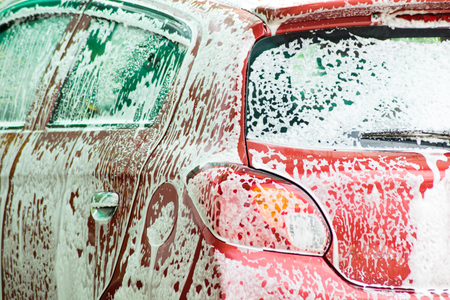 a red car is washing in foamの写真素材