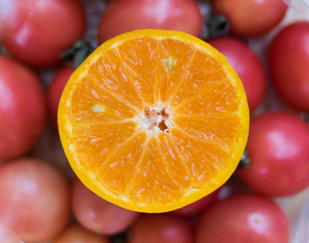 sliced orange with red tomatoes backgroundの写真素材