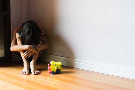 sad children,girl sitting alone in corner at homeの写真素材