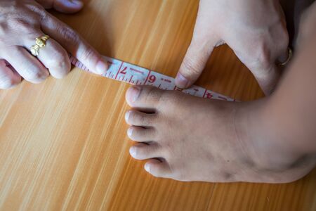 Mother holds child feet and measures the length of foot for new shoes.back to school conceptの写真素材