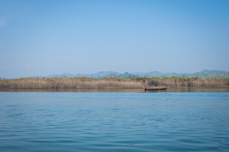 fisher man on a boat on beautiful river and mountainの写真素材
