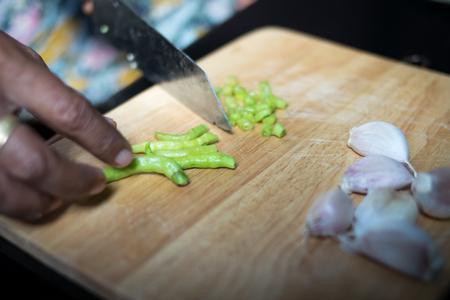 hand woman slice chili on wooden boardの写真素材