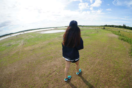 Beauty young girl Outdoors enjoying nature. Beautiful Teenage Model girl in black dress walk on the Spring Field.の写真素材