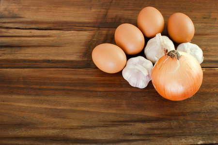 Eggs, garlic, onion on a brown wooden tableの写真素材