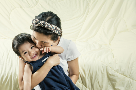 Portrait Happy Mother holds and kissing her son On the couch.の写真素材