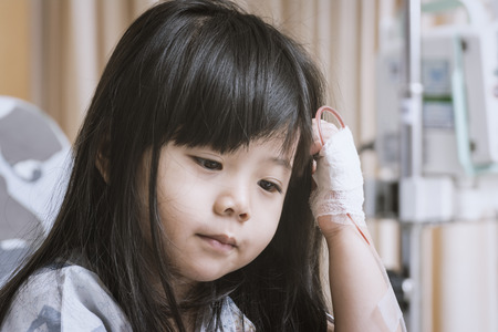 Little Cute Girl in the Hospital Sit on the patient bed  to wait for treatment.の写真素材