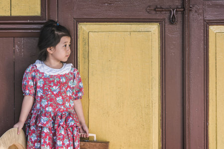 Alone Baby Asian girl while waiting for train In red long dress With lovely and copy space.の写真素材