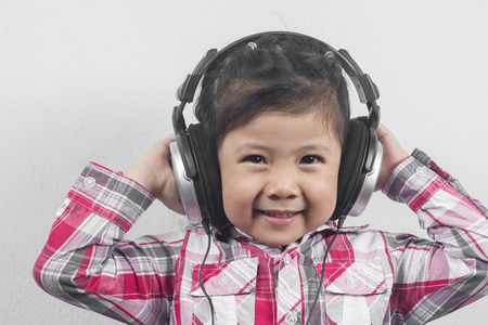 Portrait Asian Girl wear headphones with Long sleeve shirt with red pattern.の写真素材
