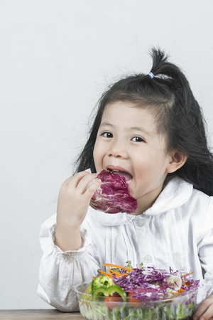 Portrait  joy of the girl who had eaten the salad, which was placed on a wooden table happily.の写真素材
