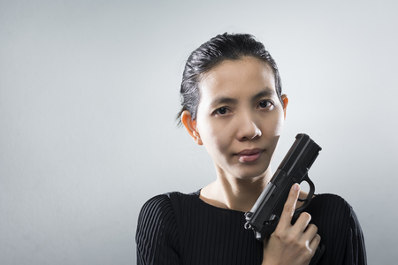 Portraits Aisan woman with a guns in hand. putting a beach on her shoulders. with space for text.の写真素材