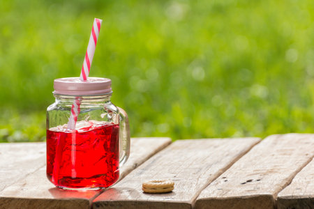 Sweet soda mixed in a glass jar with a beautiful tube and cookie on wooden table garden with space for text.の写真素材