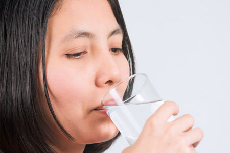A woman hands and pure water into a glass to drink. The concept of health and body care for women.の写真素材
