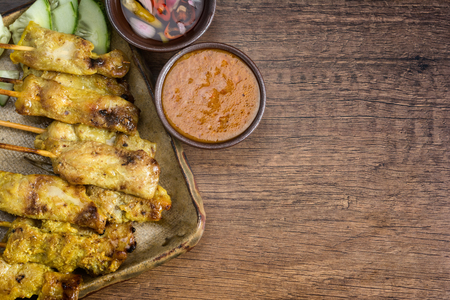 Close up Pork Satay with The sauce is delicious with cucumber on the wooden table served. with Space for Text.の写真素材