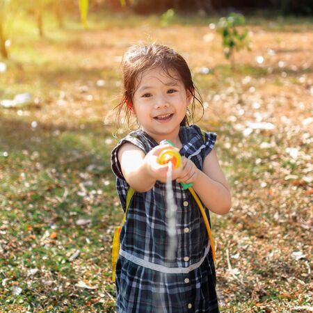 Portrait Cutle Little Asian Girl Play a fun water gun on the lawn In the summer of April.の写真素材