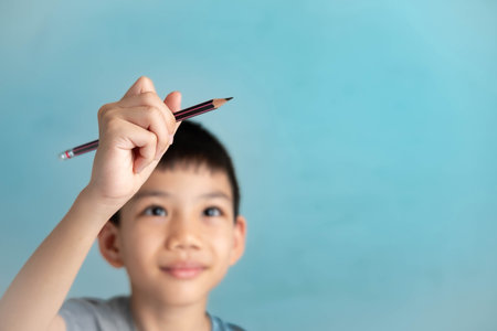 Asian boy held a pencil and drew in the air, his imagination running wild. with copy spceの写真素材