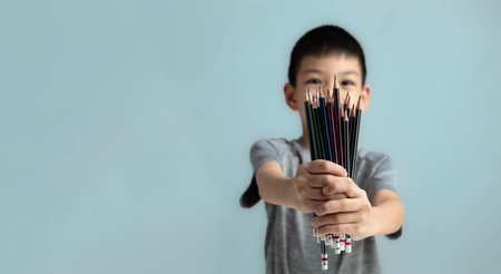 Thai Boy holding multiple pencils in his hands, showing them off, concept of the importance of school supplies.with copy space for your textの写真素材