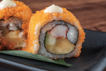 Close-up of Homemade sushi roll with orange tobiko On a black plateの写真素材