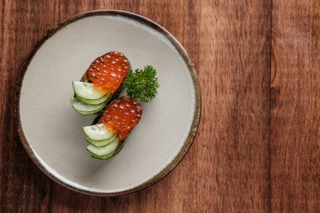 Top Table View of Ikura and Cucumber Gunkan Maki on a Round Plate with copy space for your text.