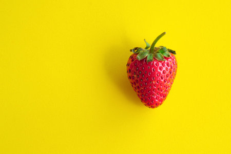 Top View of Single Strawberry on a Yellow Background with copy space for your text.の写真素材