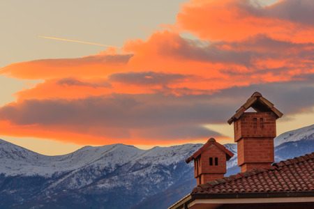 the profiles of two chimneys drawn against the background of a mountain at sunsetの写真素材