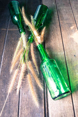 Grass in green glass bottles on the wooden backgroundの写真素材
