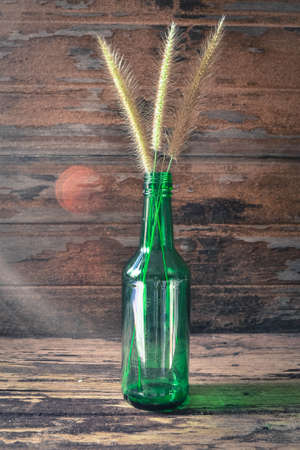 flower weed in the green bottle on a woodenの写真素材