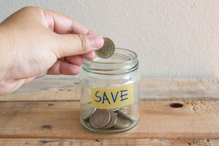 Money Saving concept , hand putting money coin inthe mug