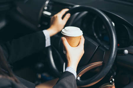 Business woman's hand holding a coffee cup to take away, she is driving in the morningの写真素材