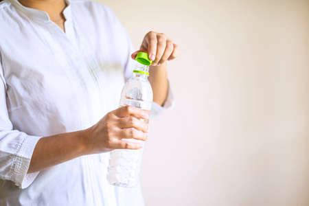 Woman's hand opening a bottle with waterの写真素材