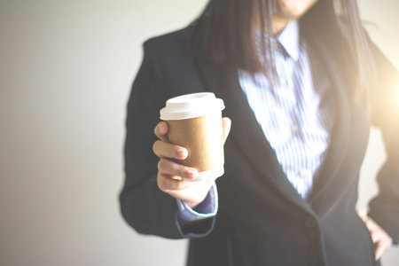 Business woman's hand holding a coffee cup to take awayの写真素材