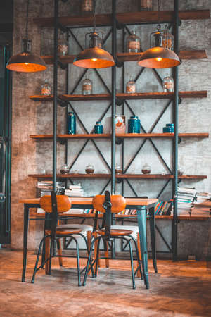 Loft living room with high ceiling, cement concrete background , design accessories loft style bookshelf, dining table with chairs.の写真素材