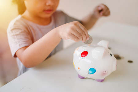 A girl saving coin into piggy bankの写真素材