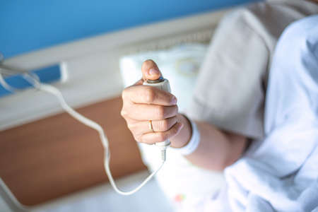 Patient pressing nurse call button holding help emergency health careの写真素材