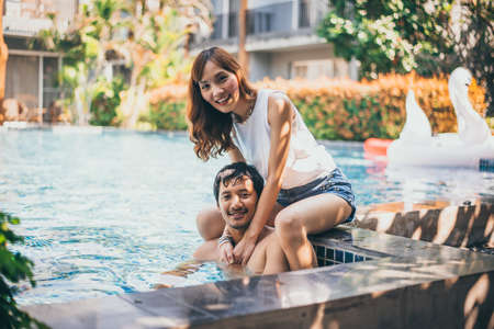 Young Asian adult couple doing in the swimming poolの写真素材