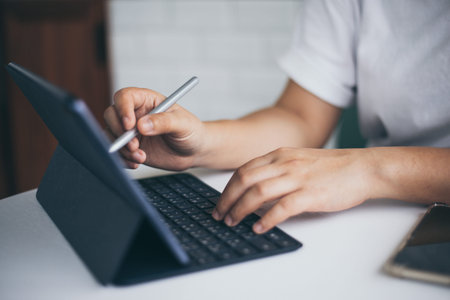 Female hands holding and using digital pen writing on taplet screen , freelance working business at homeの写真素材