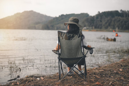 Woman relaxing on the camping chair at the riverside in the midst of nature.