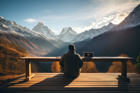 Digital nomad working on a laptop with a breathtaking mountain view. Generative AI.の素材