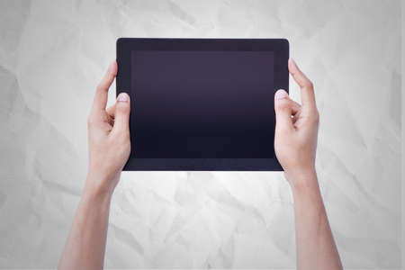 Human Hand Hold Tablet over paper background.の写真素材