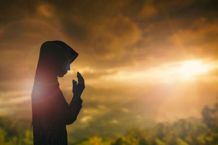 Silhouette of man with raised hands over blur cross concept for religion, worship, prayer and praise.の写真素材