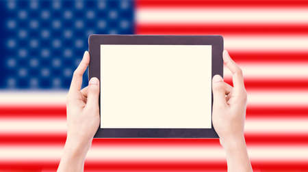Hands holding tablet on blurred USA Flag with clipping path insideの写真素材